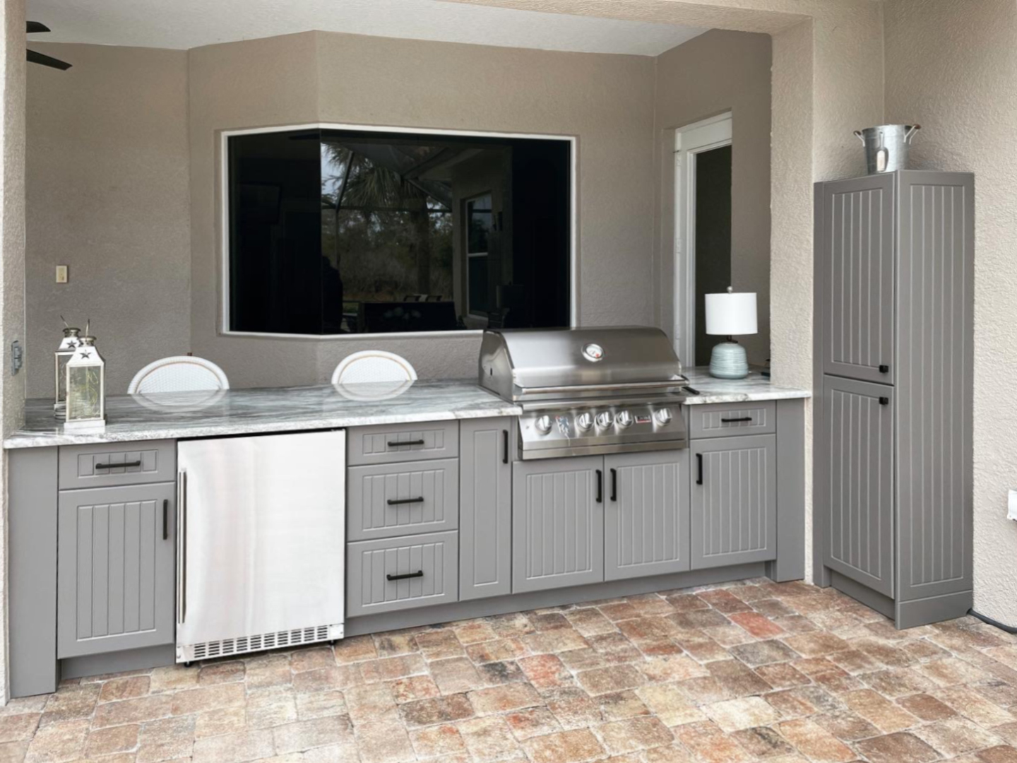 OUTDOOR KITCHEN 19. Custom outdoor kitchen ins Sarasota, FL. Kitchen features slate grey, v-groove style doors. Appliances include Lion grill, Azure stainless front refrigerator and black bar pulls.