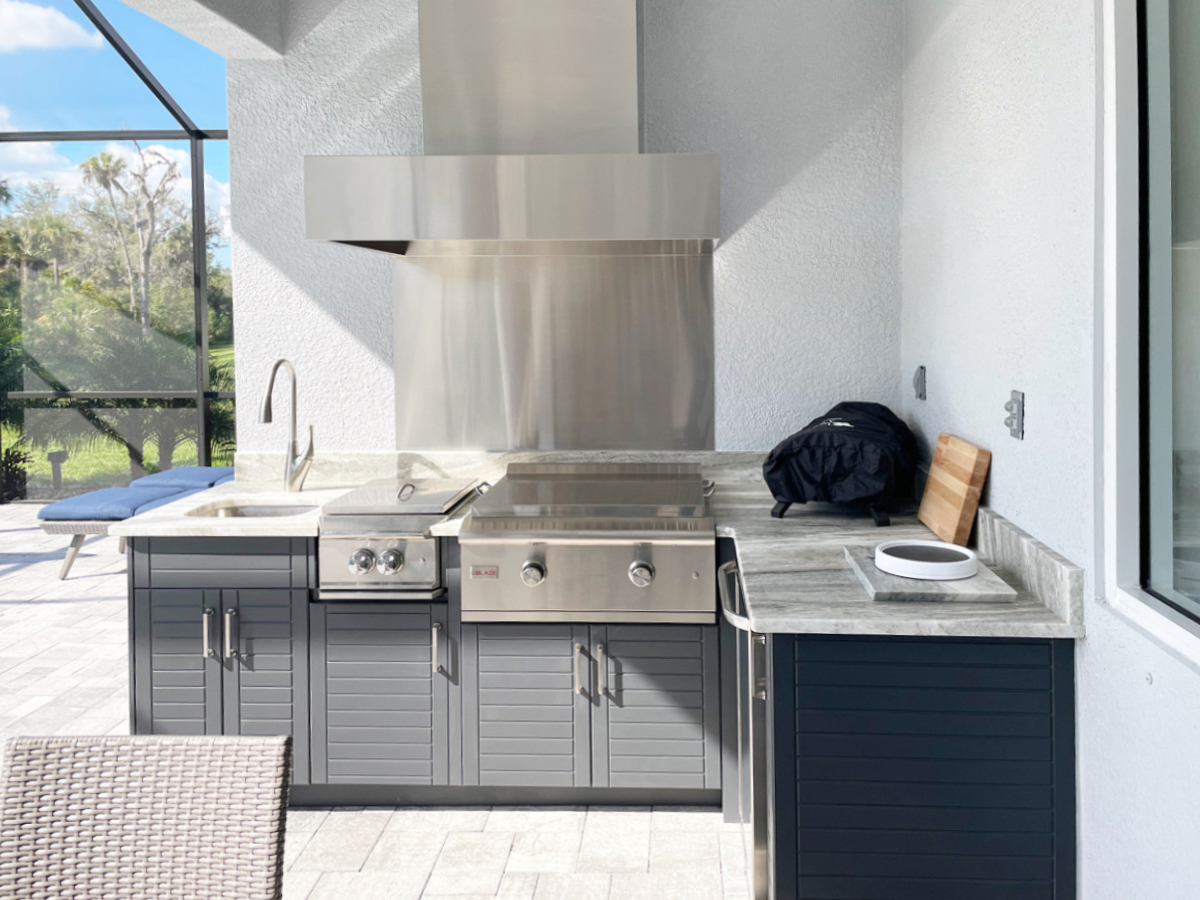 OUTDOOR KITCHEN 3. Custom outdoor kitchen in Parrish, FL. Kitchen features charcoal grey, cabana style cabinets. Appliances include Blaze griddle, Blae power burner, Heat Versa hood, stainless hood chase, and stainless backsplash & bar pulls.