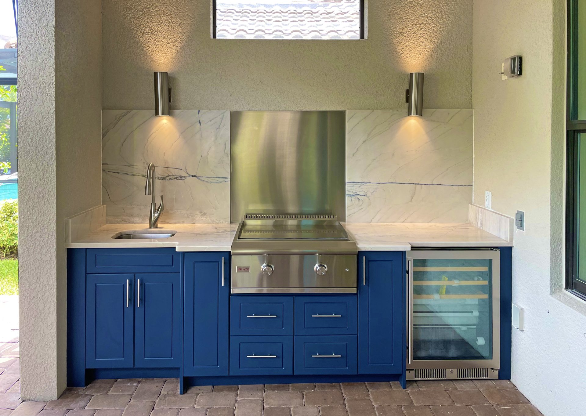OUTDOOR KITCHEN 32. Custom outdoor kitchen in Sarasota, FL. Kitchen features indigo blue, sport style cabinets. Appliances include Blaze griddle, stainless backsplash, Azure glass front refrigerator and stainless bar pulls.