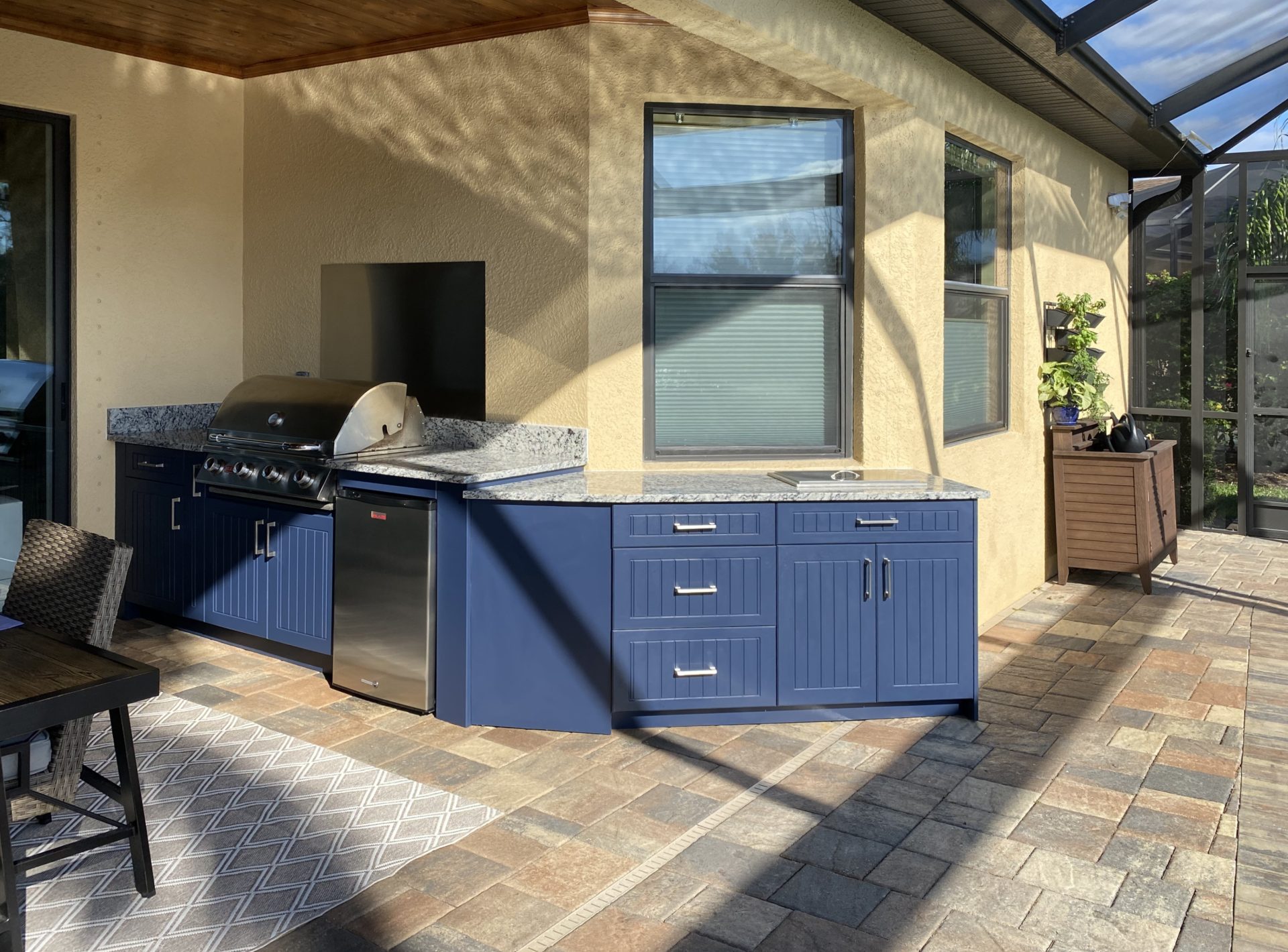 OUTDOOR KITCHEN 38. Custom outdoor kitchen in Lakewood Ranch, FL. Kitchen features indigo blue, v-groove style cabinets. Appliances include Lion grill, Blaze stainless front refrigerator and stainless backsplash & bar pulls.
