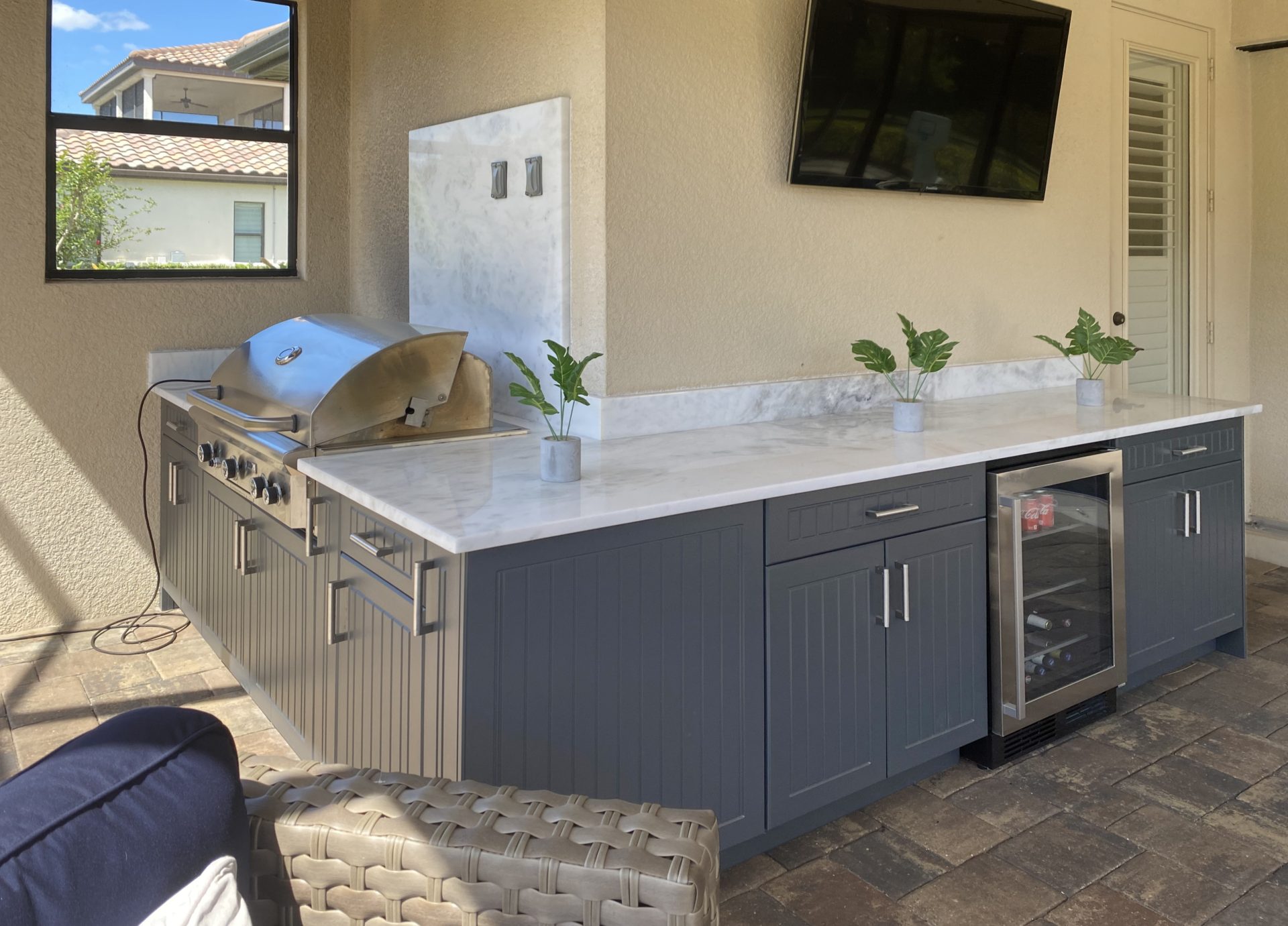 OUTDOOR KITCHEN 40. Custom outdoor kitchen in Sarasota, FL. Kitchen features charcoal grey, v-groove style cabinets. Appliances include Lynx grill, glass front refrigerator and stainless bar pulls.
