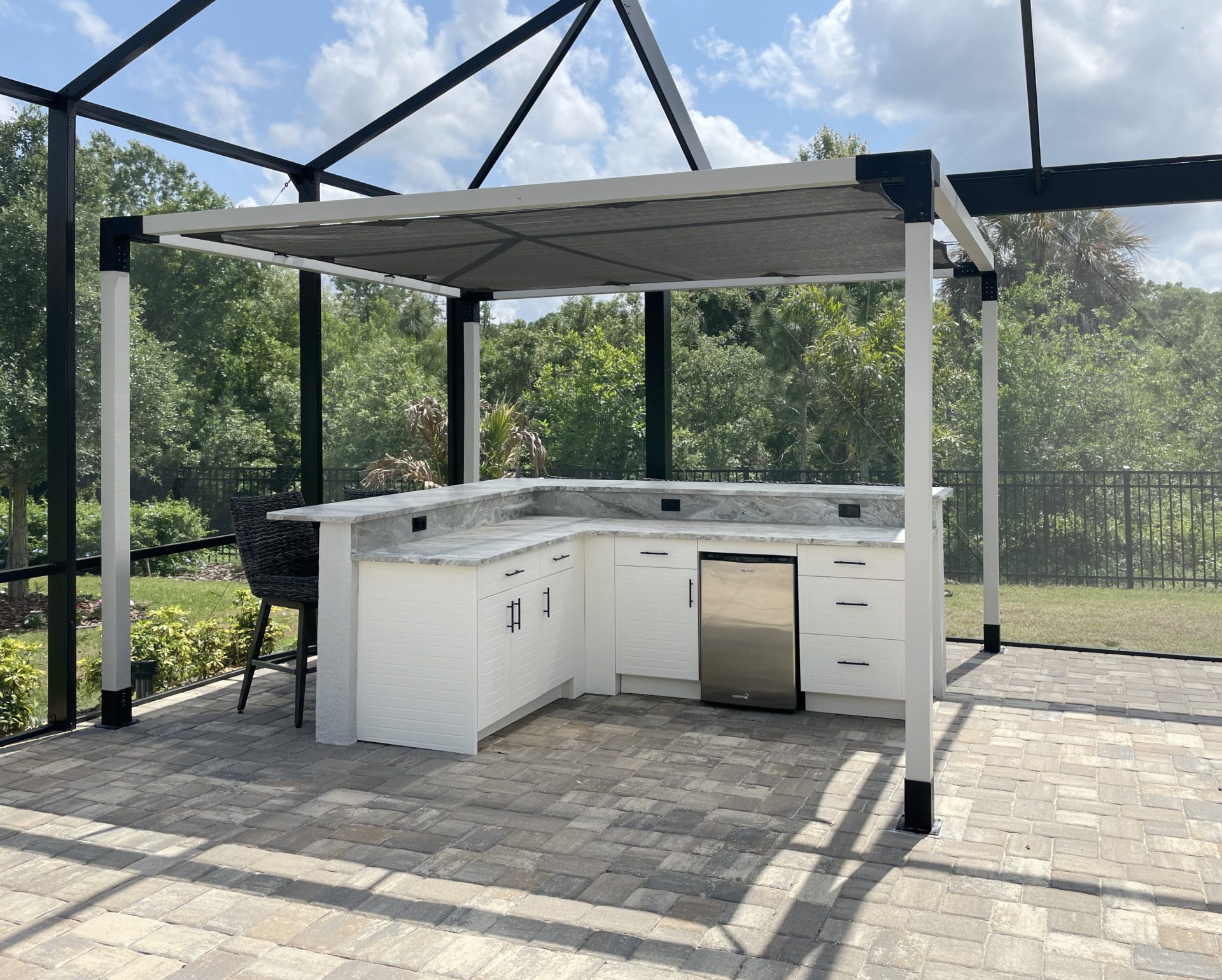 OUTDOOR KITCHEN 41. Custom outdoor kitchen in Lakewood Ranch, FL. Kitchen features seafoam, cabana style cabinets. Appliances include Blaze stainless front refrigerator and black bar pulls.