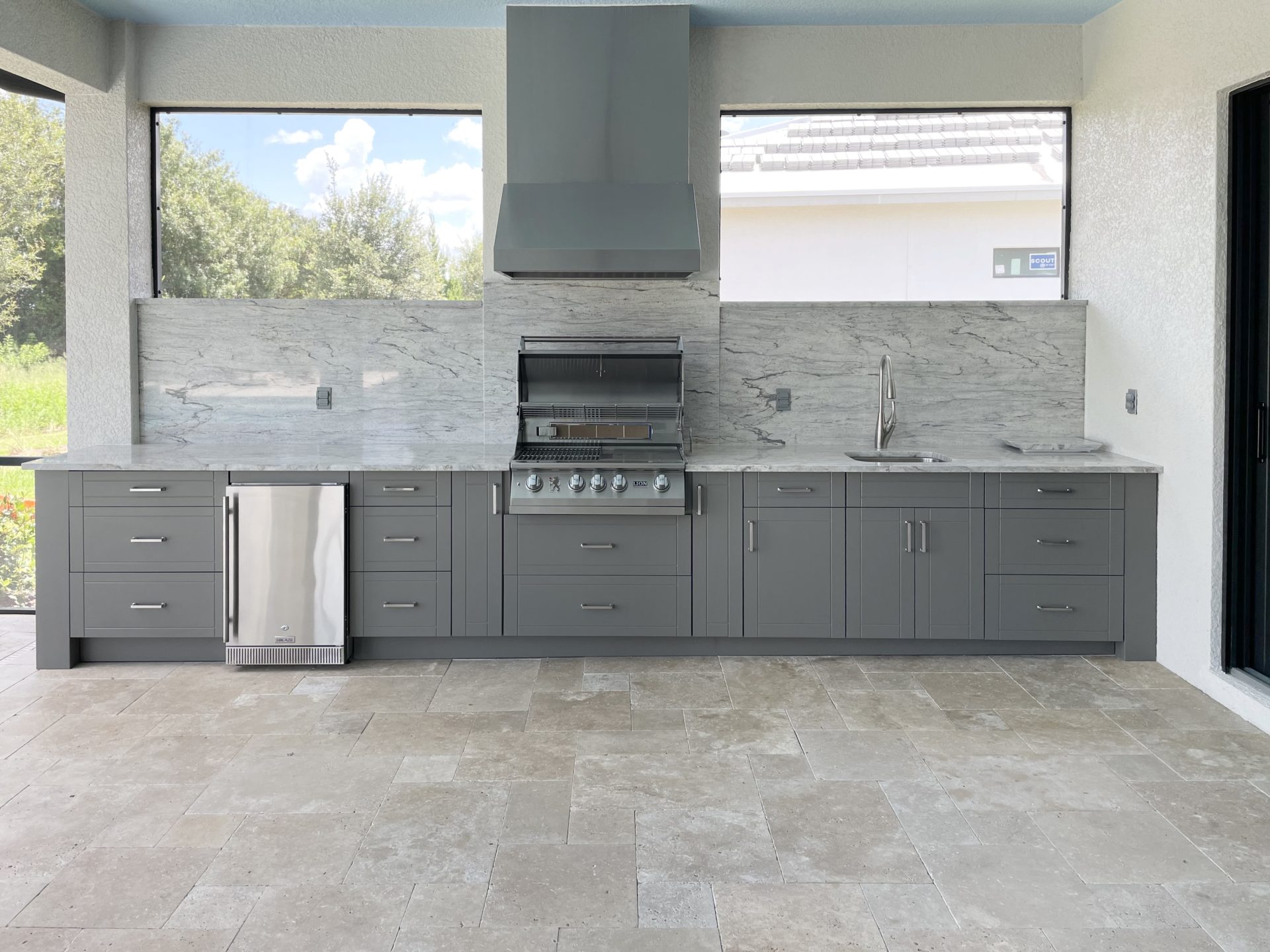OUTDOOR KITCHEN 9. Custom outdoor kitchen in Lakewood Ranch, FL. Kitchen features slate grey, shaker style cabinets. Appliances include Lion grill, Cypress outdoor hood, stainless hood chase, Blaze stainless refrigerator and stainless bar pulls.